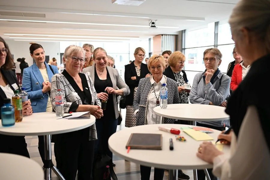 Eine Gruppe von Frauen steht um Tische mit Papieren und diskutiert angeregt.